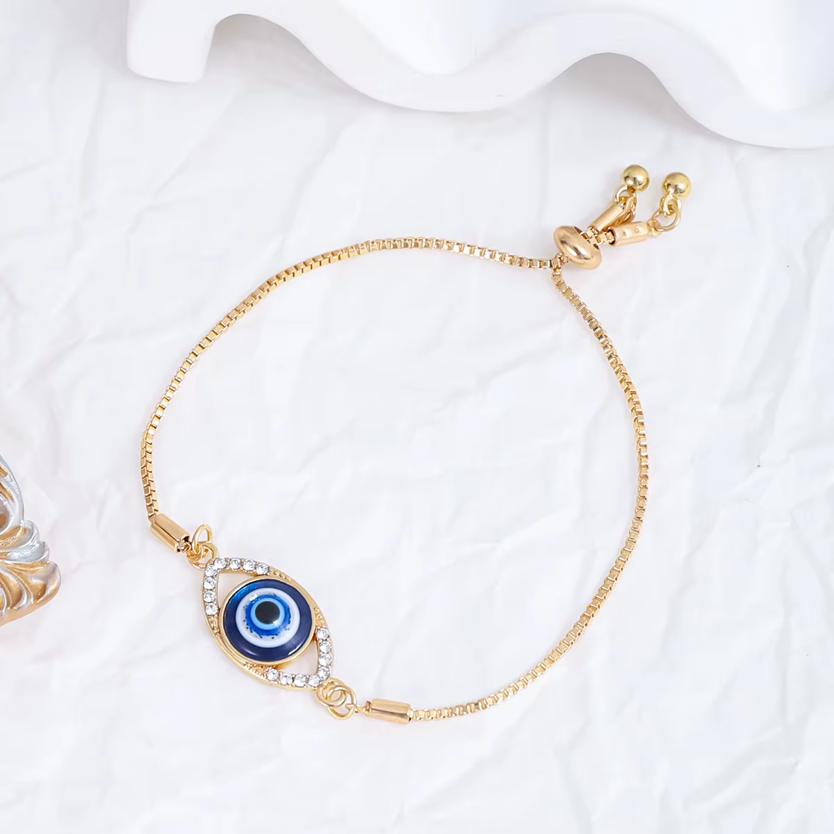 Bracelet ajustable plaqué or avec œil porte-bonheur, chaîne en maille forçat incrustée d'émail bleu 